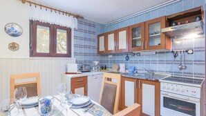 Una cocina compacta con armarios de madera, horno integrado y comedor con mesa dispuesta para cuatro.