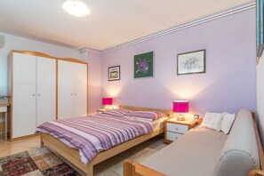 A bedroom with a bed, a nightstand, a dresser, and a sofa.