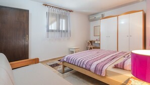 Un dormitorio con cama, escritorio, armario y ventana con cortinas.