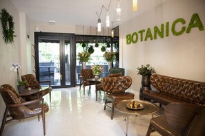 A lobby with leather sofas, a coffee table, and potted plants. - Hotel Botanica (Belgrade)