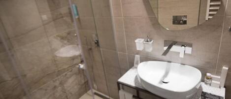 A modern bathroom with a glass shower enclosure, a white sink, and a mirror.