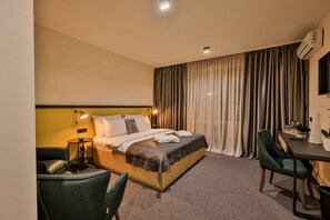 A hotel room with a bed, a desk, a chair, a lamp, and a television. - Hotel Botanica (Belgrade)
