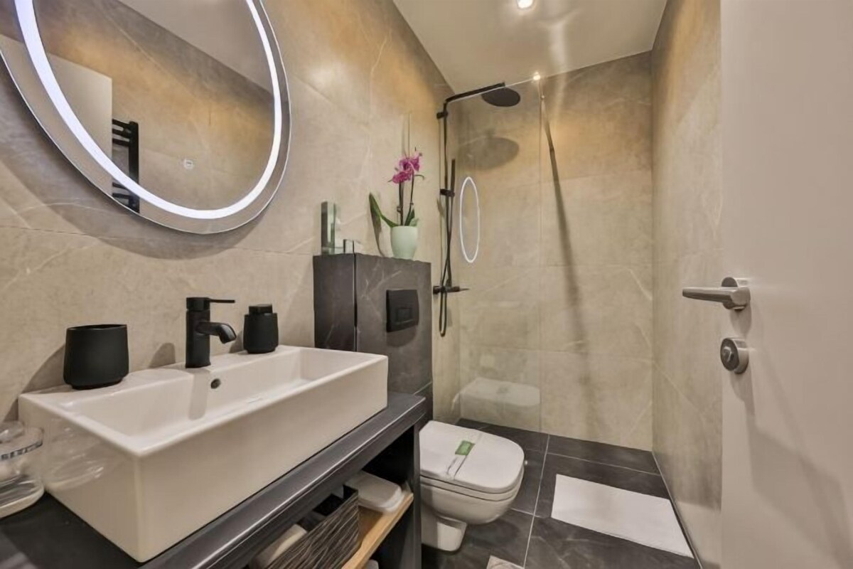 A modern bathroom with a large sink, toilet, and shower.