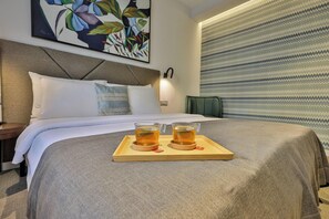 A hotel room with a bed, pillows, a tray with two glasses of tea, and a painting on the wall. - Hotel Botanica (Belgrade)