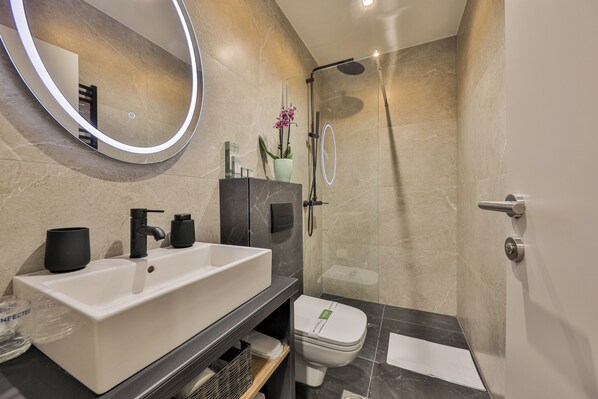 A modern bathroom with a white sink, black faucet, and a glass shower enclosure. - Hotel Botanica (Belgrade)