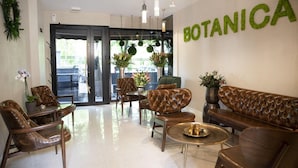 A lobby with leather sofas, a coffee table, and potted plants.