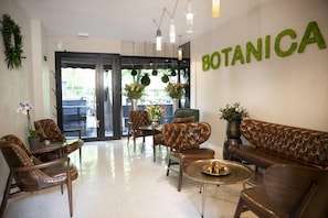 Un hall dâentrĂ©e avec des canapĂ©s en cuir, une table basse et des plantes en pot.