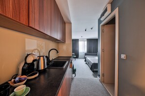 Une chambre d’hôtel de taille réduite, équipée d’une kitchenette, d’un lit et d’une salle de bain.