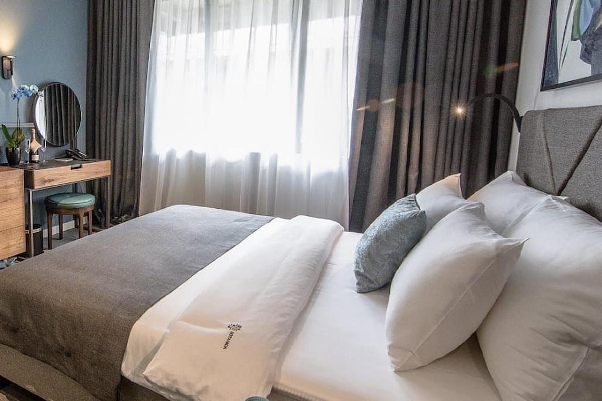 A modern hotel room with a bed, a desk, and a chair.