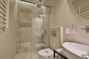 A bathroom with a glass shower enclosure, a white toilet, and a large white sink. - Hotel Botanica (Belgrade)