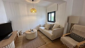 Un salon moderne avec un canapé, une table basse, un téléviseur et une lampe.