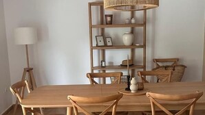 Une table à manger en bois avec quatre chaises, une étagère en osier et un lampadaire.