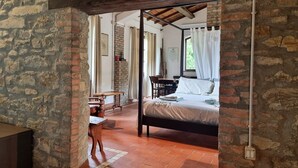 Une pièce rustique avec un lit, une table en bois et un mur en briques.