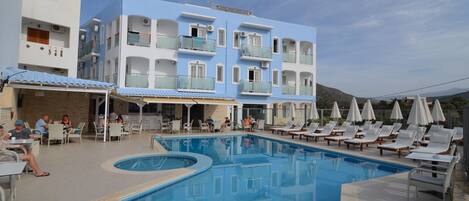 A hotel with a swimming pool, outdoor seating, and a mountain view.
