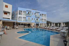 A hotel with a swimming pool, outdoor seating, and a mountain view. - Areti Hotel (Agios Vasileios)