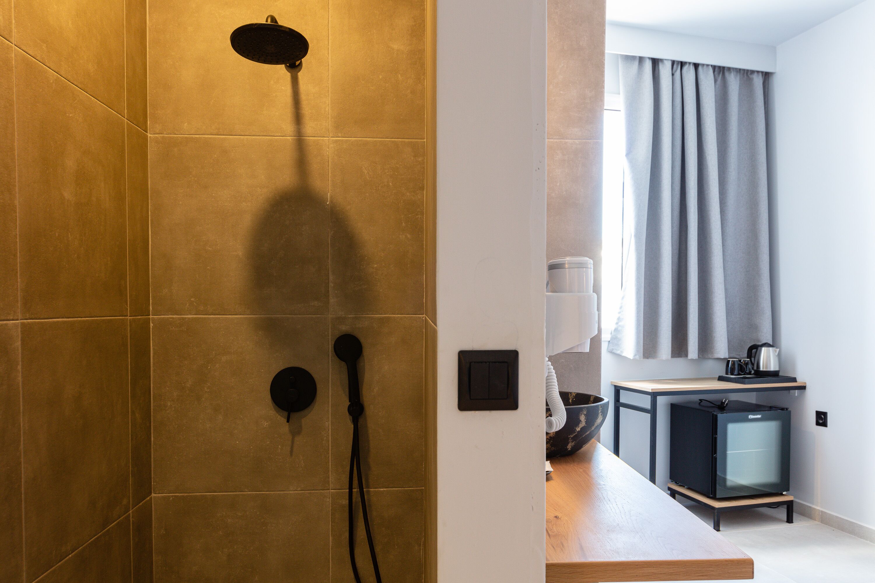 Ein modernes Badezimmer mit Dusche, Waschbecken und einem kleinen Kühlschrank.