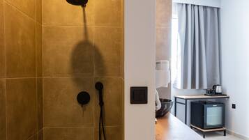 Ein modernes Badezimmer mit Dusche, Waschbecken und einem kleinen Kühlschrank.