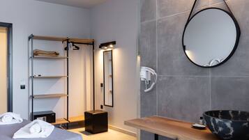 A modern hotel room with a large mirror, a wooden vanity, and a built-in shelf with towels.