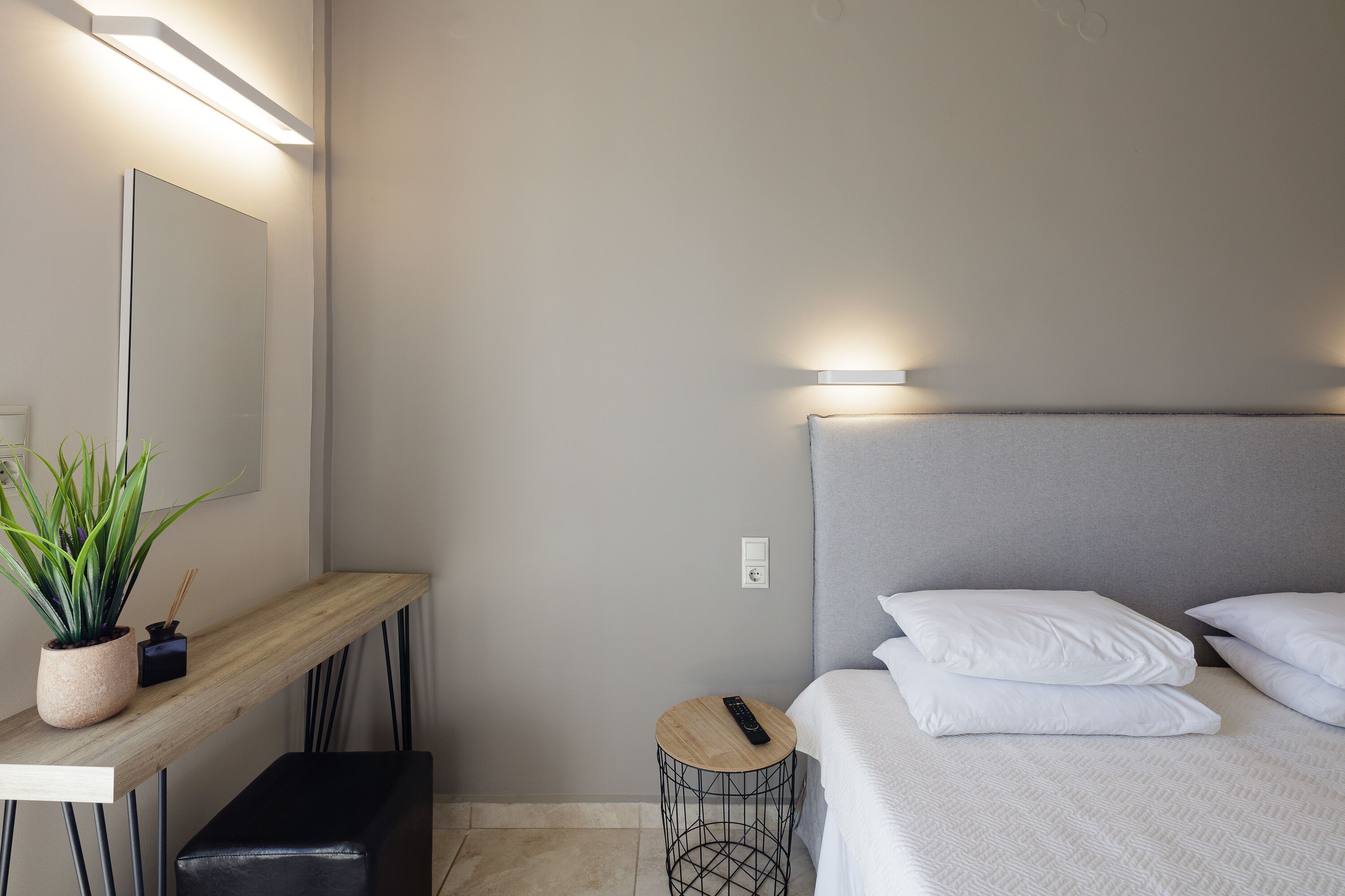A modern hotel room with a bed, bedside table, and a small round table with a remote control.