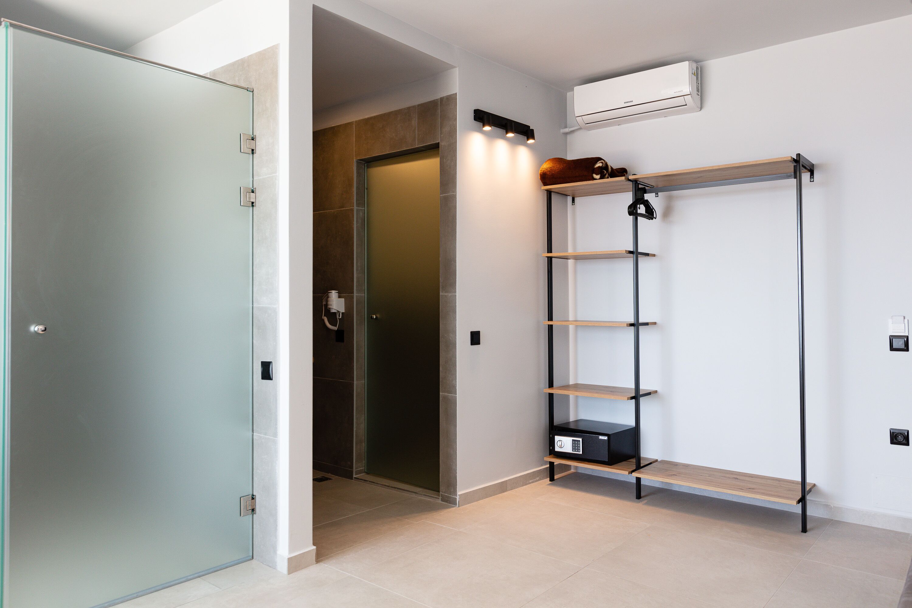 Een moderne badkamer met een douchecabine van glas, een houten wastafelmeubel en een ingebouwde plank.