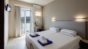 A hotel room with a large bed, a TV mounted on the wall, and a balcony with curtains. - Areti Hotel (Agios Vasileios)
