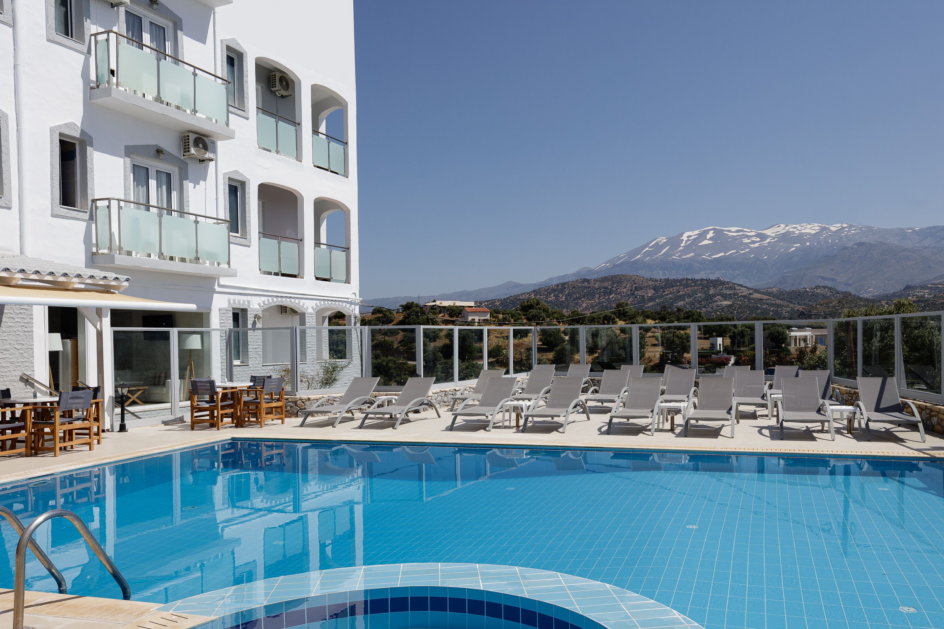A pool area with lounge chairs and a view of a mountain.