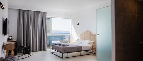 Un dormitorio moderno con cama, escritorio y vista al exterior.