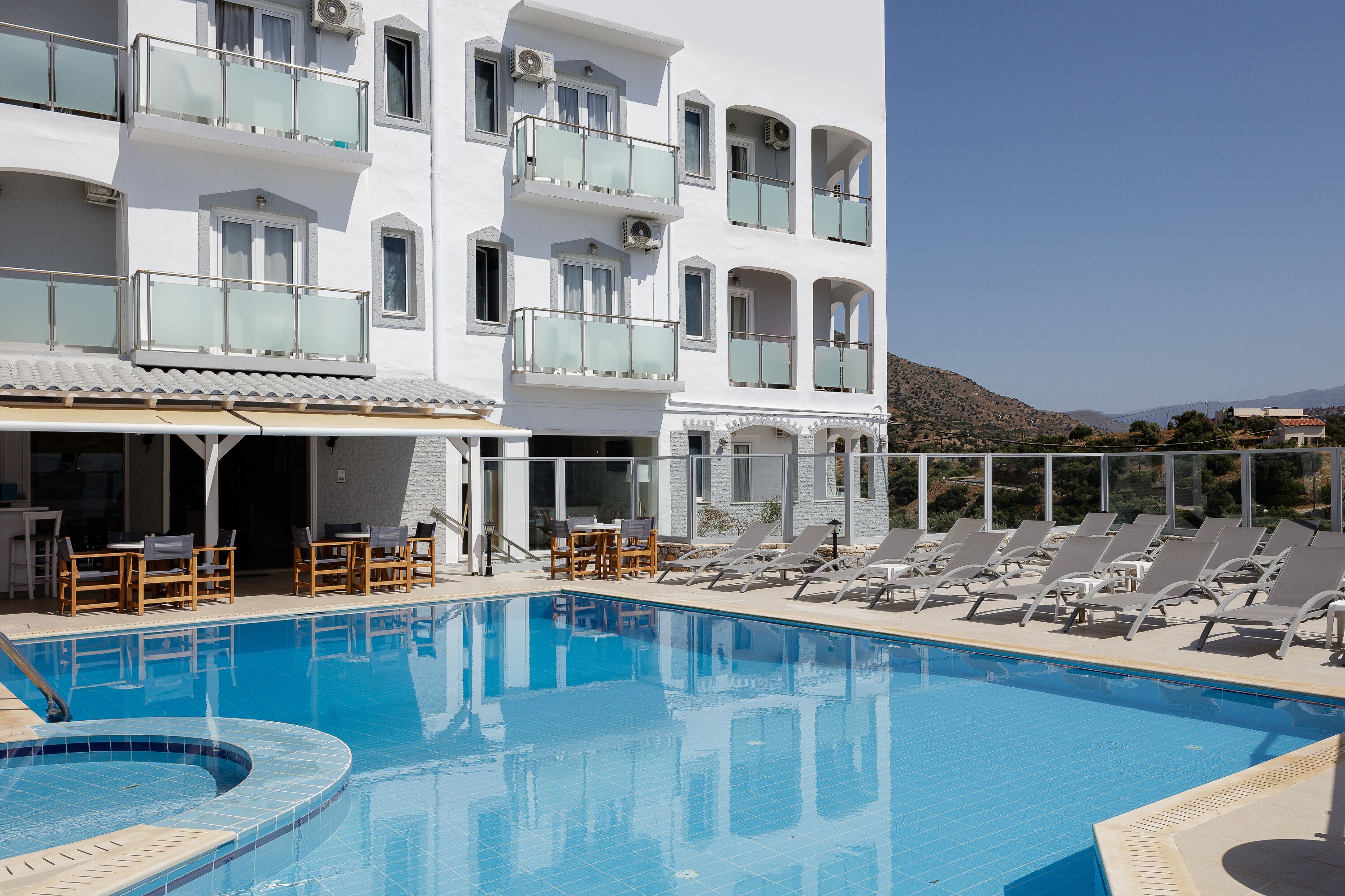 Ein Hotel mit Schwimmbad, Liegestühlen und Bergblick.