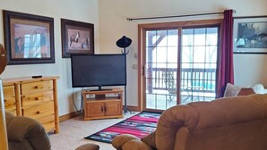Una sala de estar con techo de madera, televisor, sofá, sillón y aparador de madera.