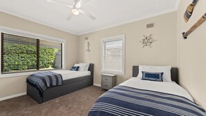 A bedroom with two beds, a ceiling fan, and a window with blinds. - Moorooba Pet Friendly Holiday Home Nelson Bay (Nelson Bay)