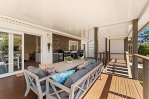 An outdoor deck with a dining table, chairs, and a grill area.