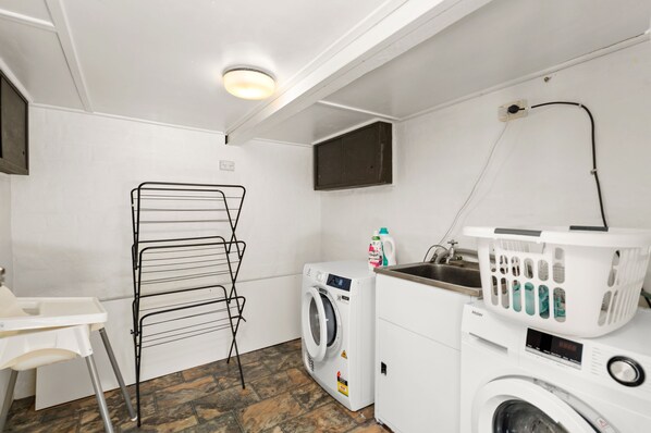A laundry room with a washing machine, dryer, and a drying rack.