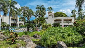 Un resort con piscina, palmeras y una pequeña cascada.