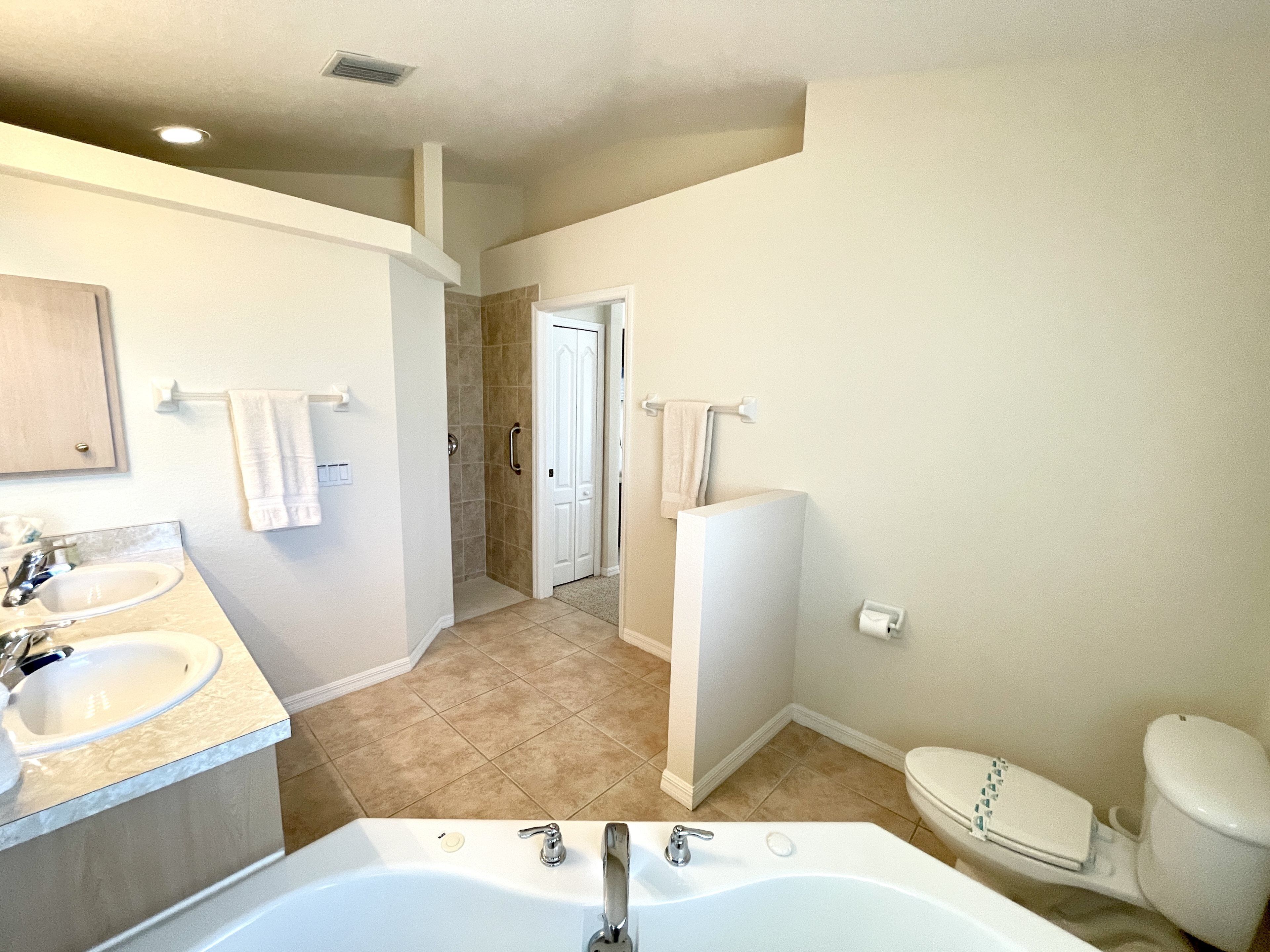 A bathroom with a bathtub, two sinks, a toilet, and a shower.