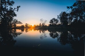 Een rustig meer bij zonsondergang, bomen weerspiegelen in het water.