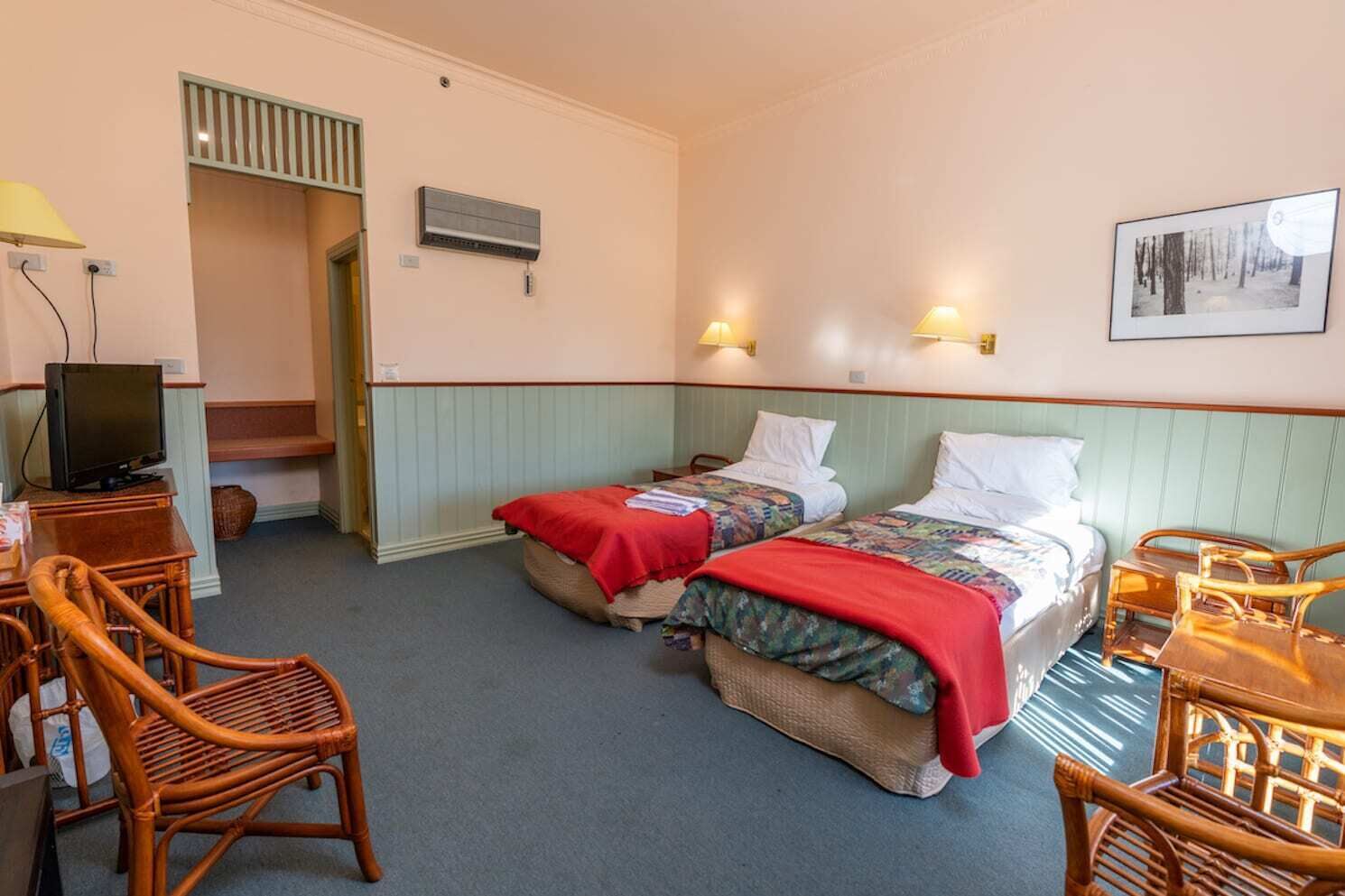 Une chambre d’hôtel avec deux lits, une télévision et un bureau avec des chaises.