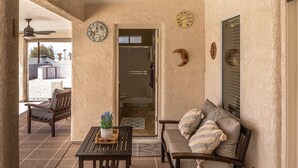 A room with a sofa, a table with a plant, a ceiling fan, and a door leading to a bathroom. - Tropical Heated Pool & Sunset Views Oasis (Lake Havasu City)