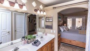 A bathroom with a large mirror, two sinks, and a vanity with wooden cabinets. - Tropical Heated Pool & Sunset Views Oasis (Lake Havasu City)