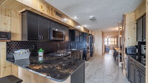 Une cuisine moderne avec des meubles noirs, un plan de travail en granit et un four à micro-ondes.