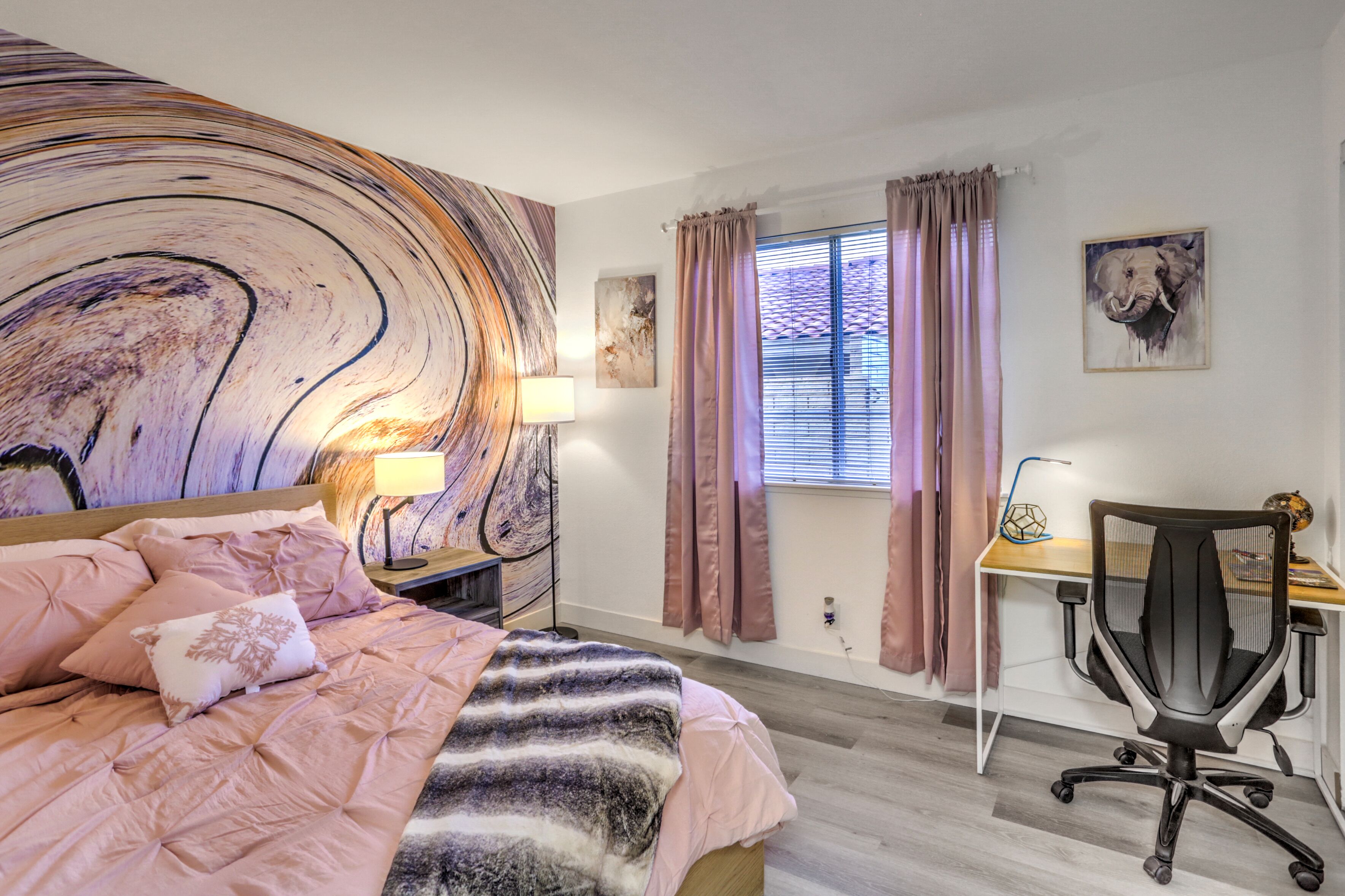 A bedroom with a bed, a desk, and a chair.