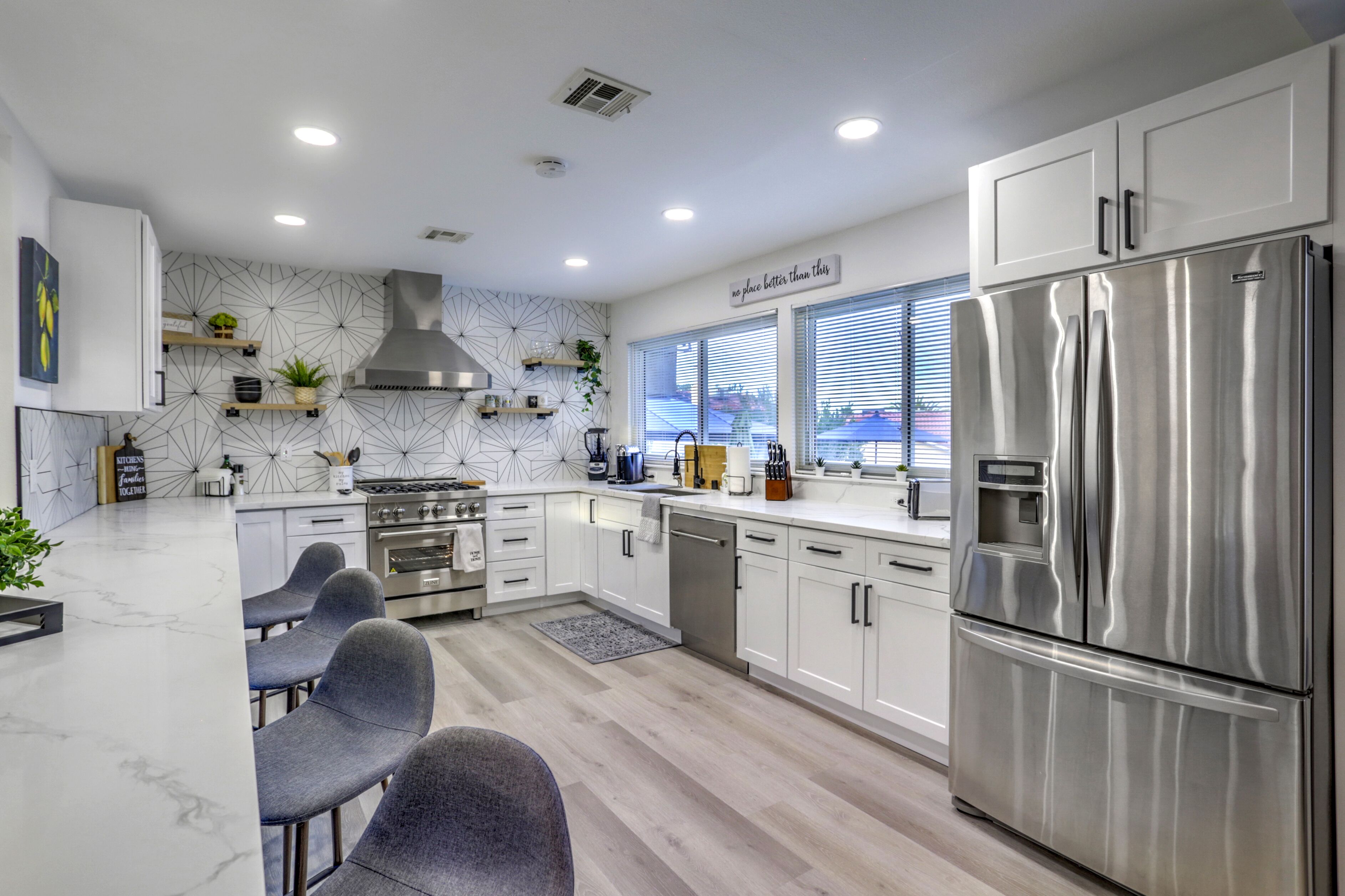 A modern kitchen with white cabinets, stainless steel appliances, and a marble countertop.