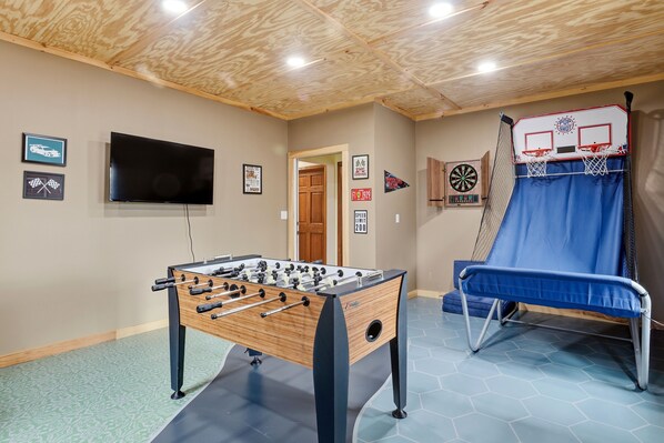 A room with a foosball table, a television, a dartboard, and a blue chair. - 3 Bdrm Spacious Home w Game Room. Just minutes from WGI & Wine Trail. (WATKINS GLEN)
