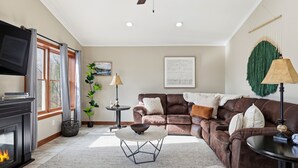 Ein Wohnzimmer mit Kamin, einem braunen Ledersofa, einem runden Couchtisch und einem Fernseher.