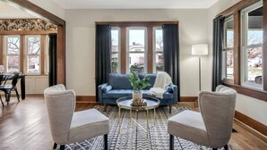 Un salón con un sofá azul, dos sillones, una mesa de centro y un tapete estampado.