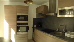 A modern kitchen with wooden cabinets, a stainless steel sink, and a built-in oven.