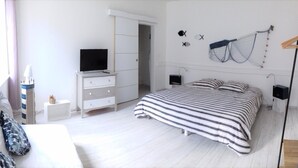 A bedroom with a bed, a TV, a dresser, and a wardrobe.