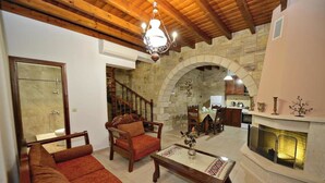 A spacious living area with a fireplace, wooden furniture, and stone walls. - May offer!!! Book at a discounted rate, valid until 31st May.  (Phalasarna)