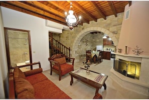 A spacious living area with a fireplace, wooden furniture, and stone walls.