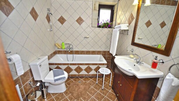 Un bagno con un water, una vasca, un lavandino e uno specchio.