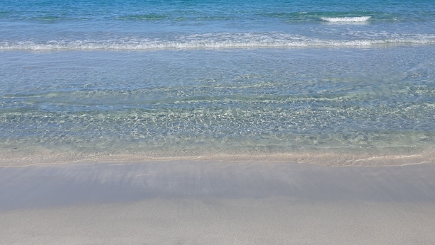 Een strand met helderblauw water en een zandstrand.